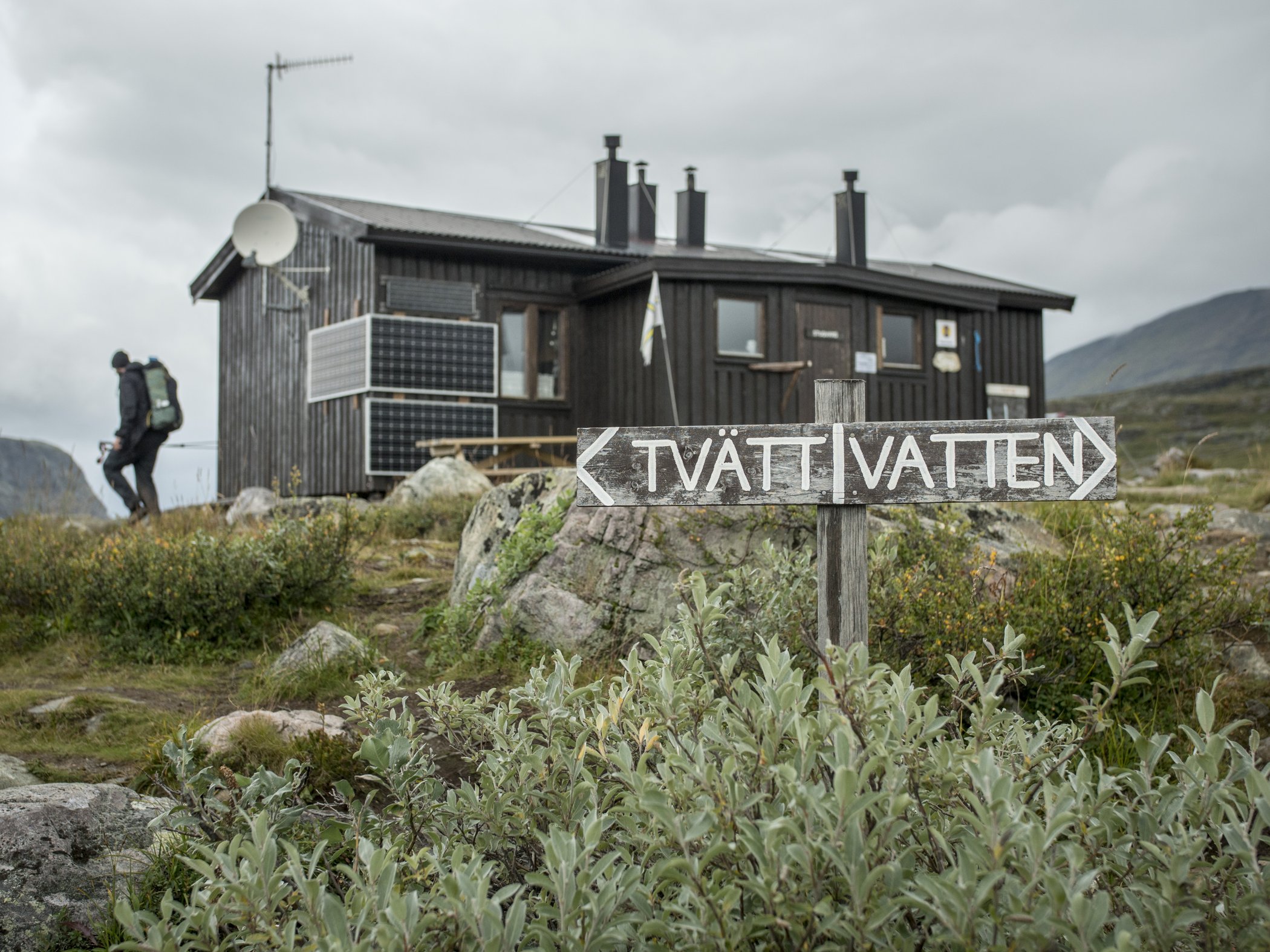 Sign pointing to washing water near a mountain hut.