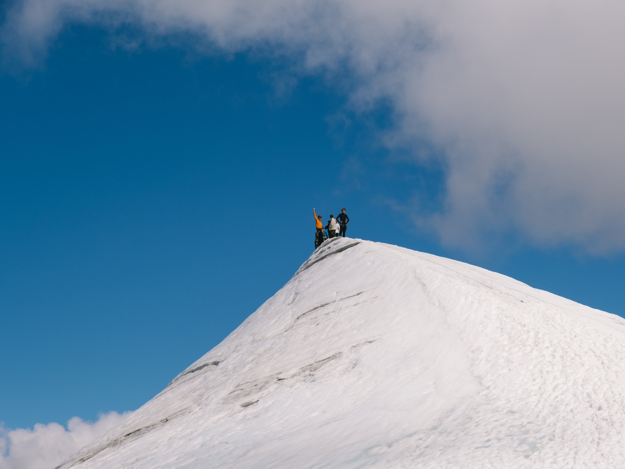 People standing on a snow-covered mountain summit.