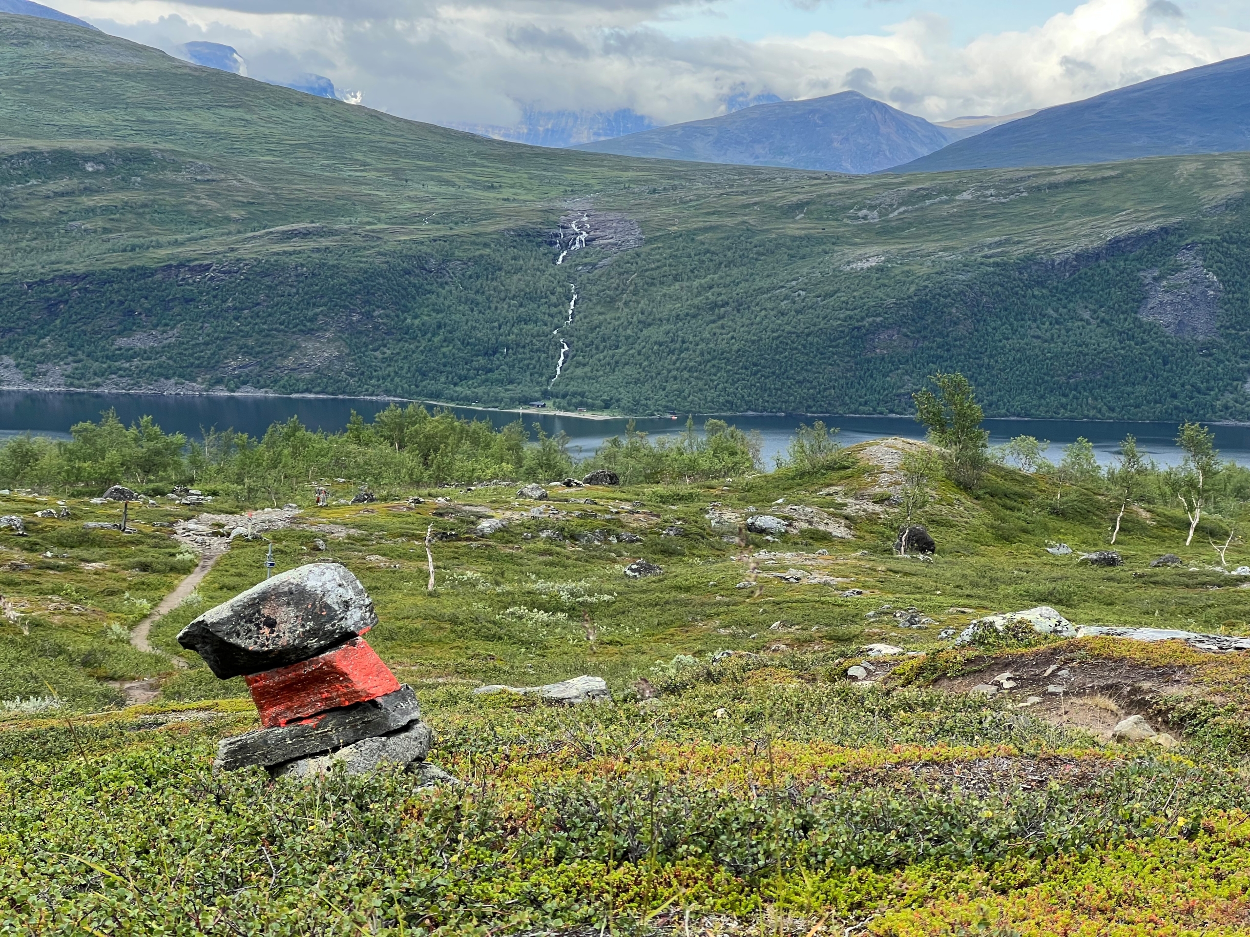 Trail marker overlooking a mountain lake and valley.
