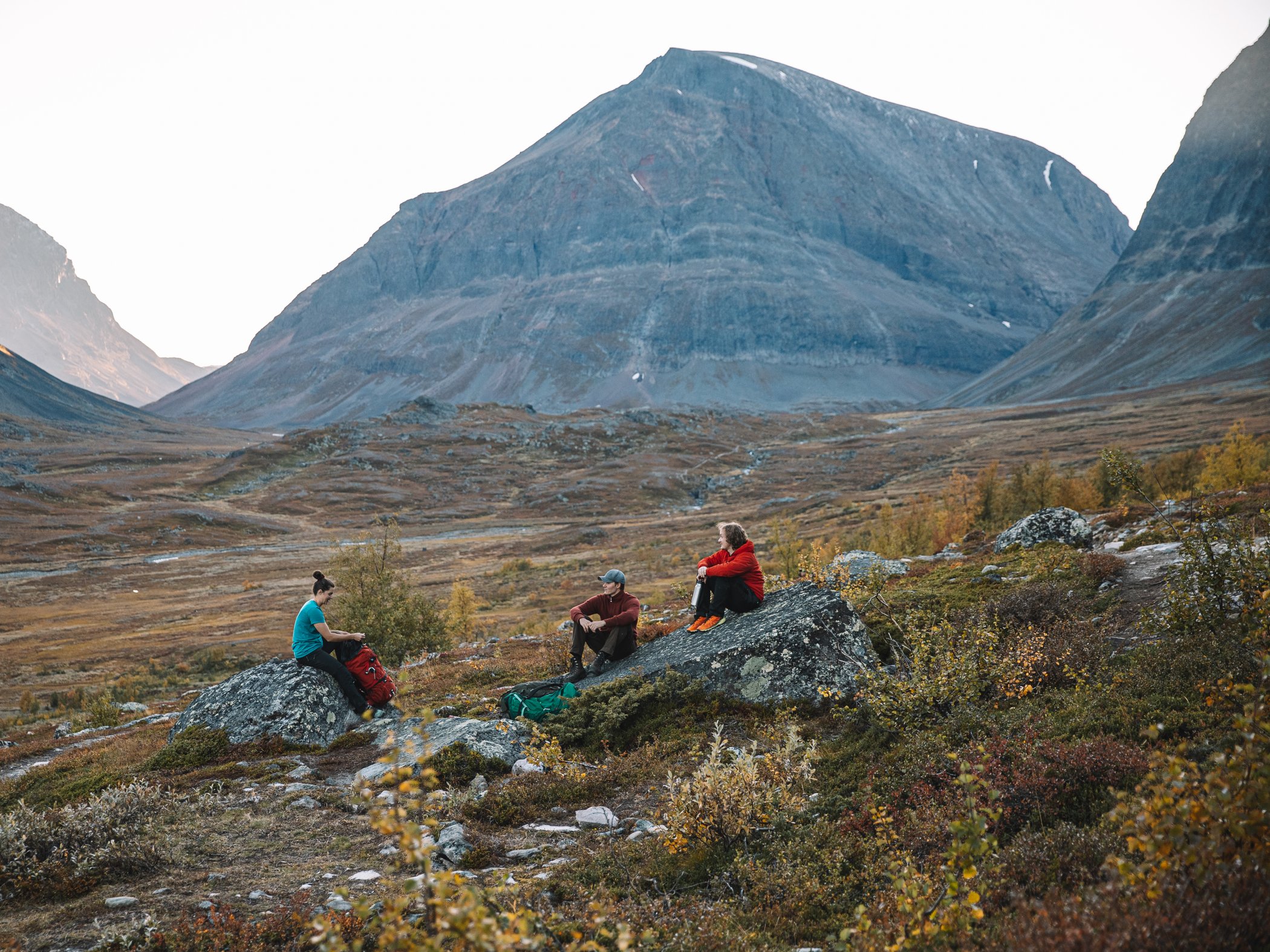 Hikers resting in a mountain valley with peaks in the background.