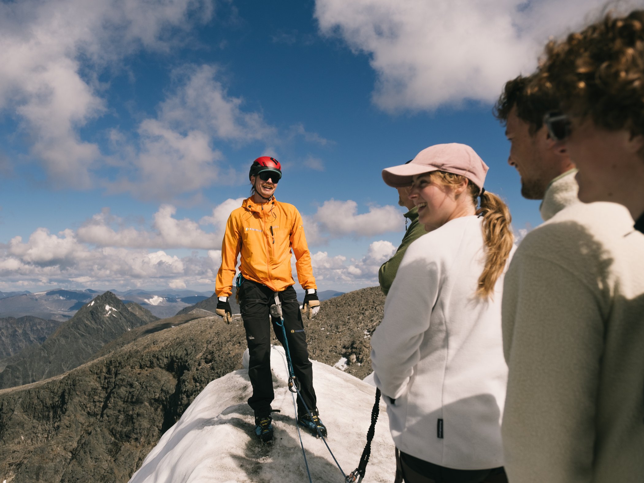 Mountain guide with a group on a snowy summit.