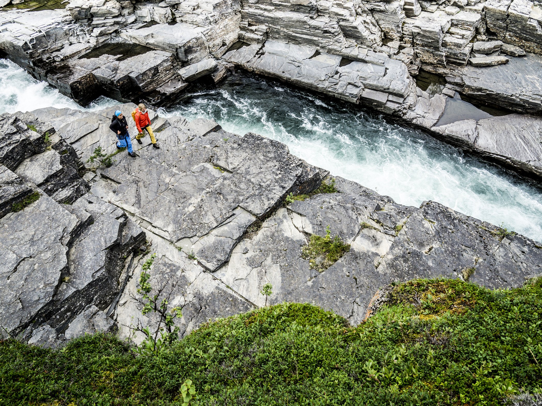 Hikers beside a mountain river in Abisko.