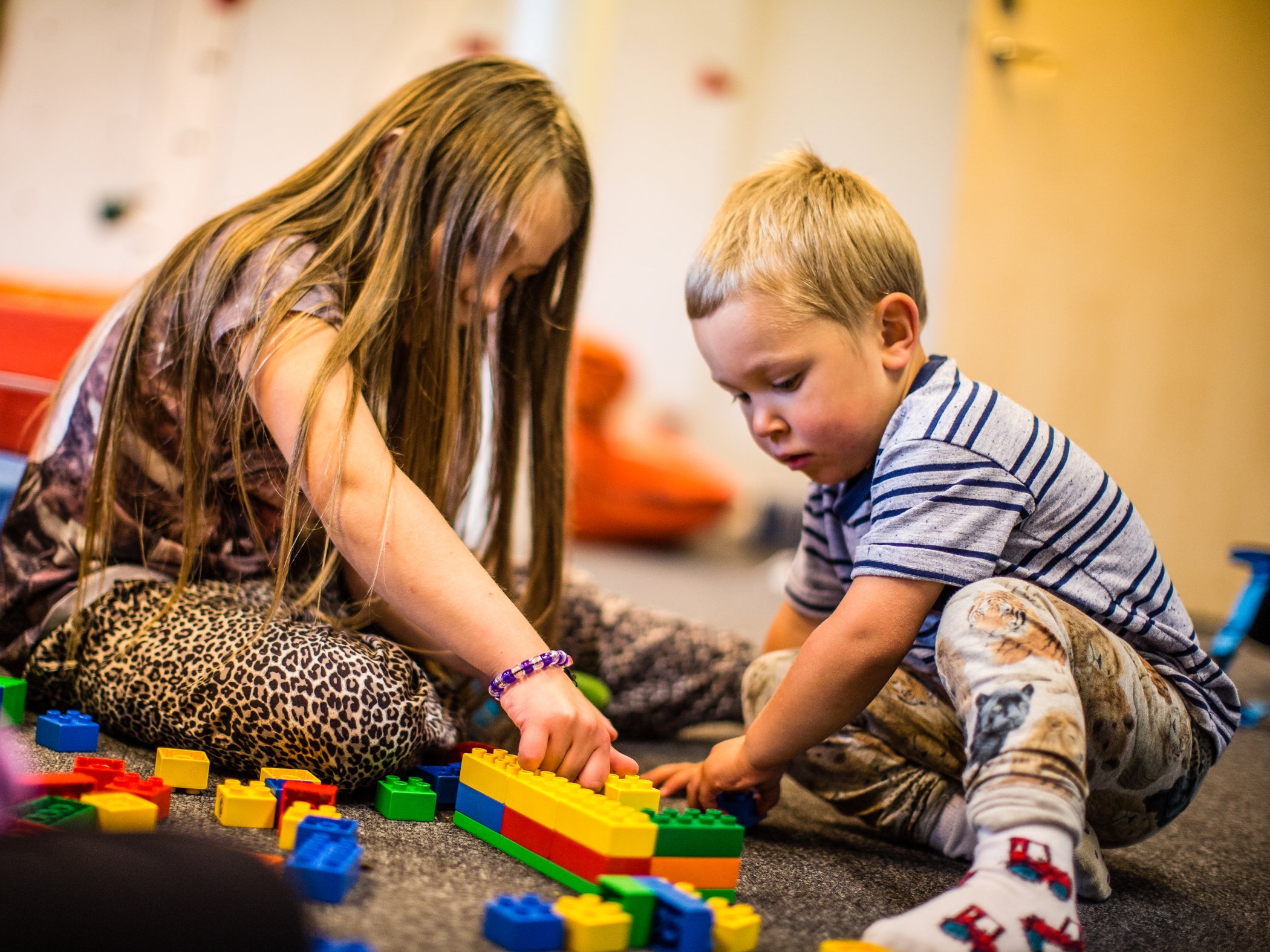 Two children building with colourful toy blocks indoors.