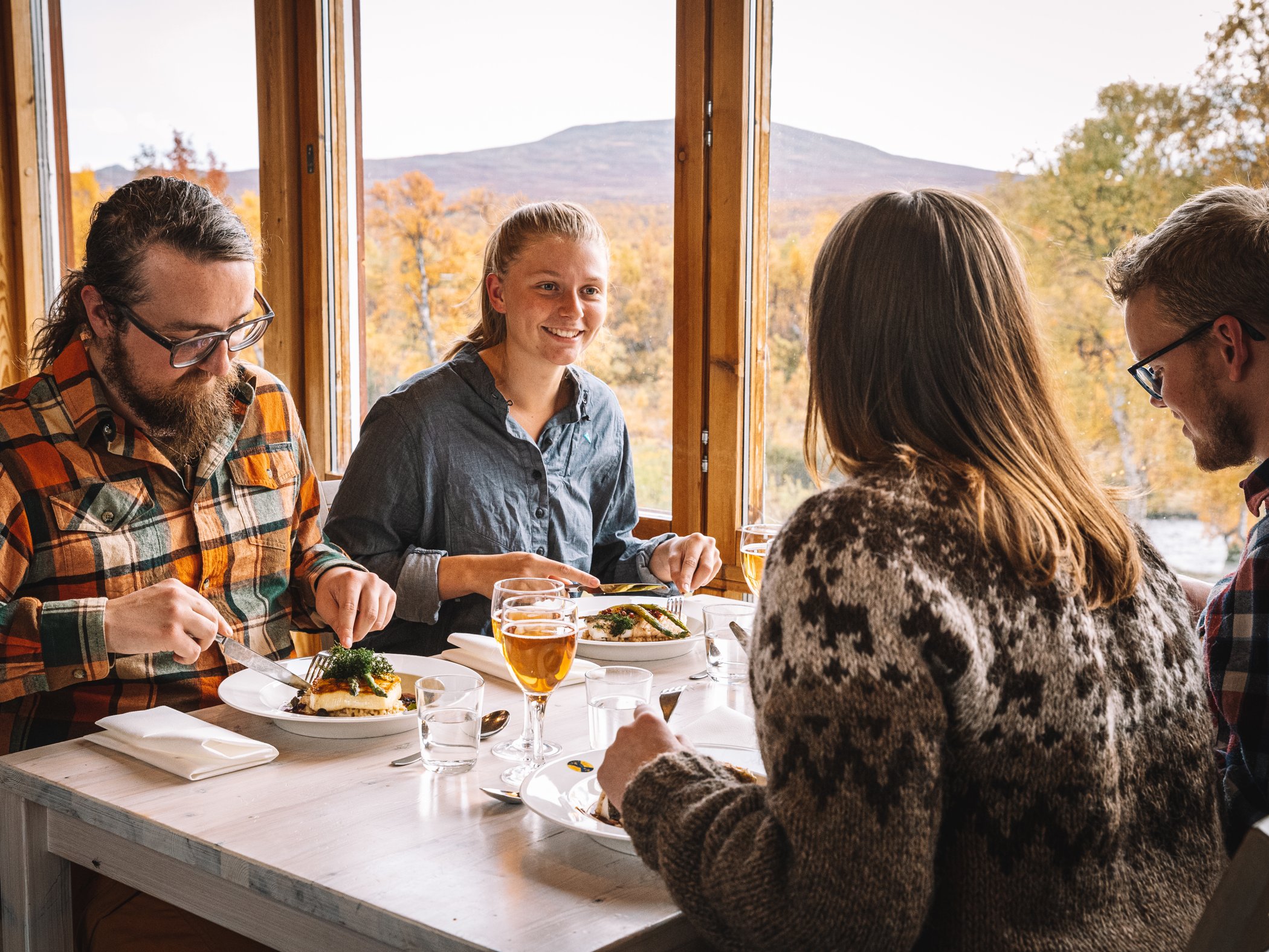 Group enjoying a meal by a window with mountain views.