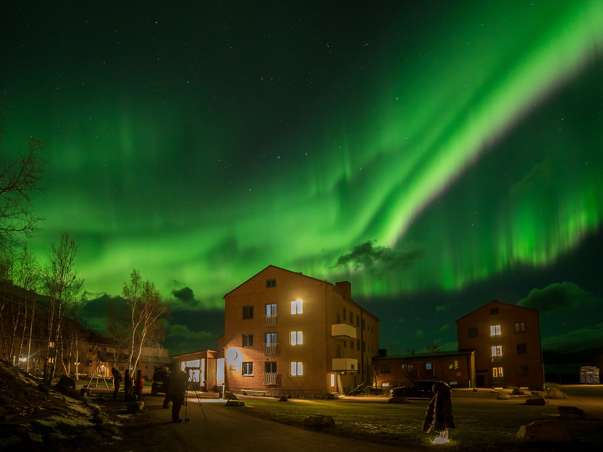 Northern lights shining above STF Abisko Mountain station on a dark winter evening.