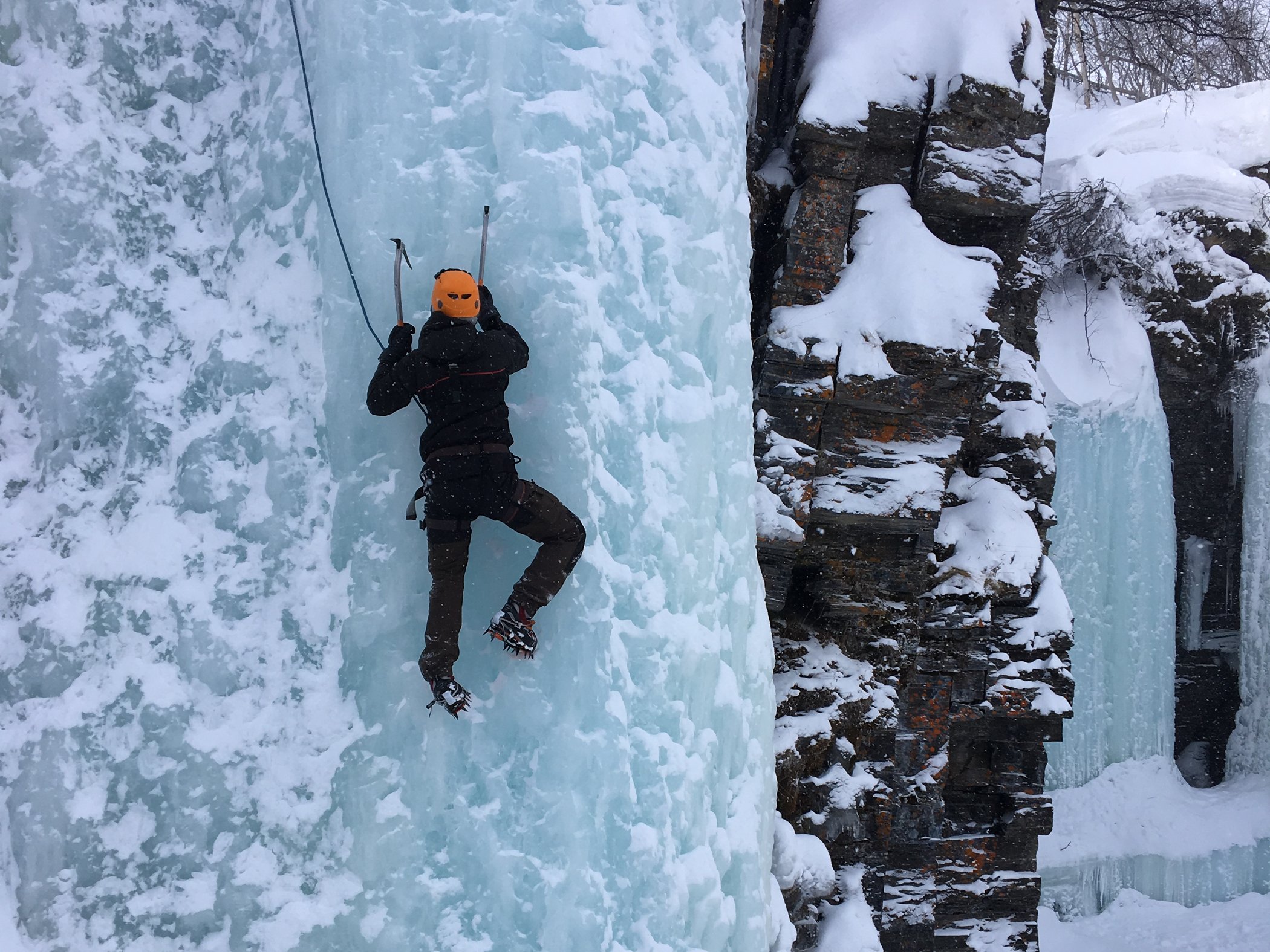 Participant climbs a frozen ice wall during an ice climbing activity in Abisko.