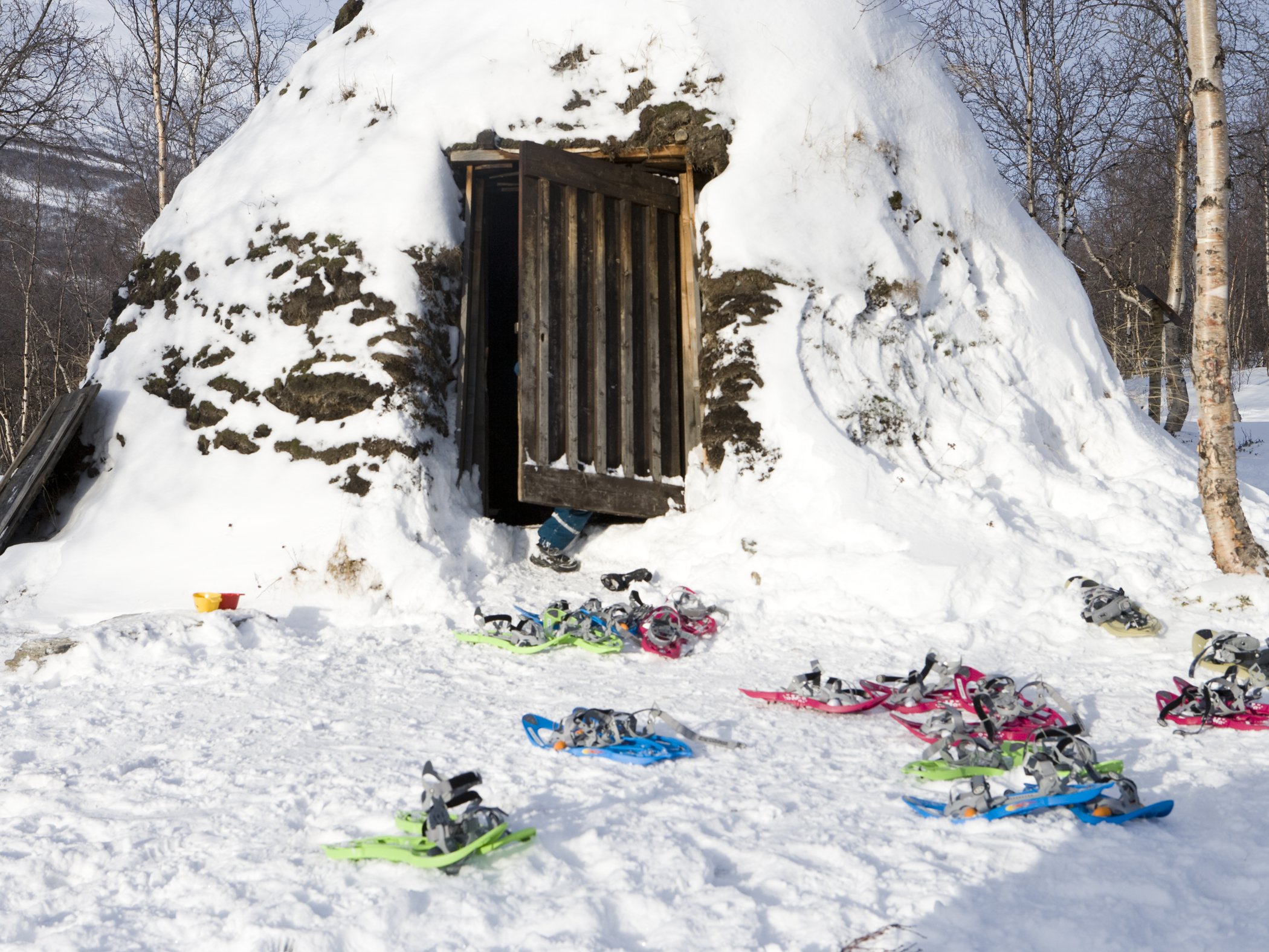 Snowshoes outside a snow-covered snow shelter in a winter landscape.